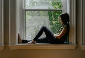 A person sitting quietly by a window in a reflective moment