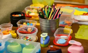 Colourful craft materials on a table, including pencils, paper shapes and craft punches.